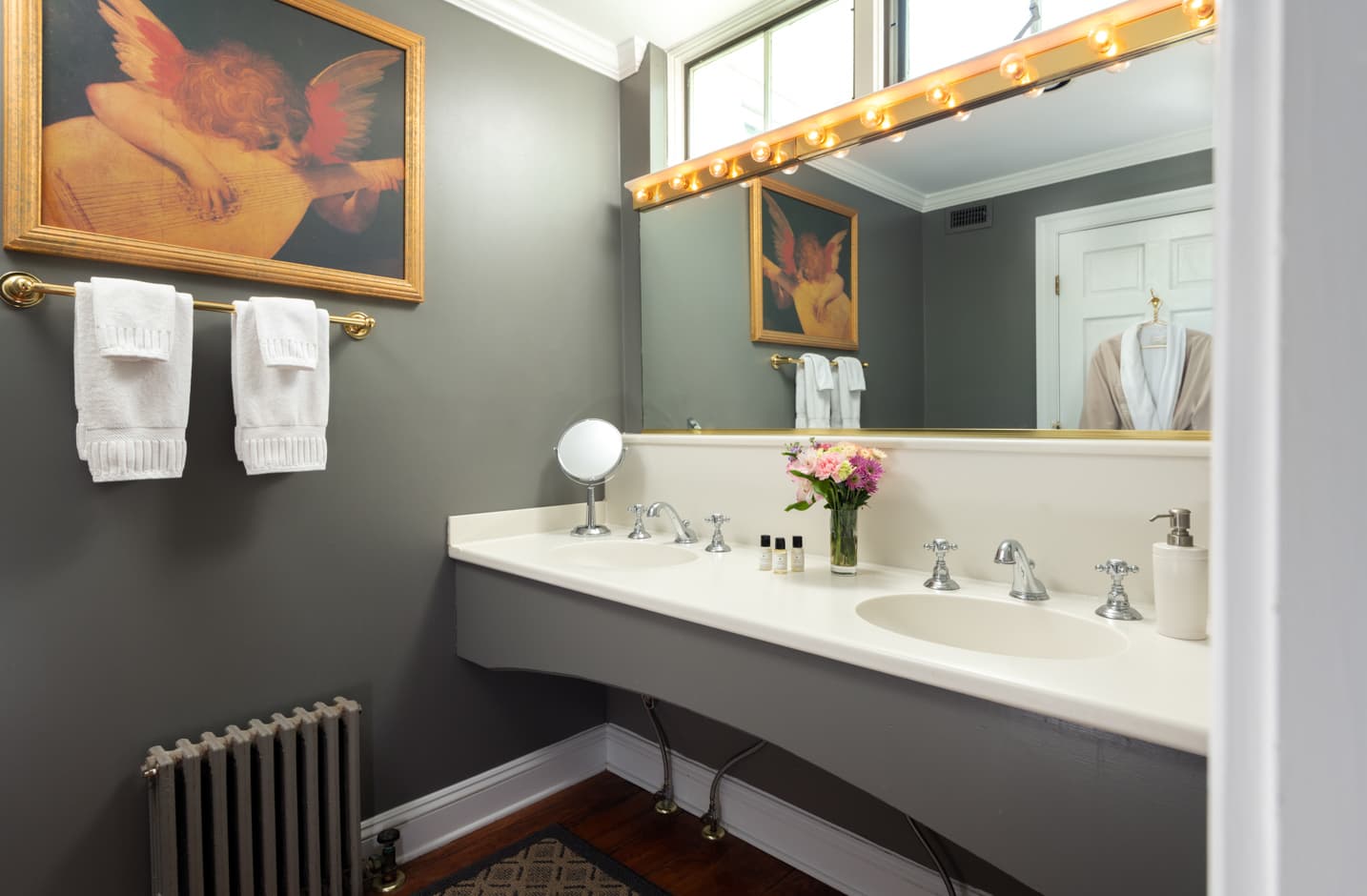Bathroom with a double vanity sink a large mirror and art on the wall