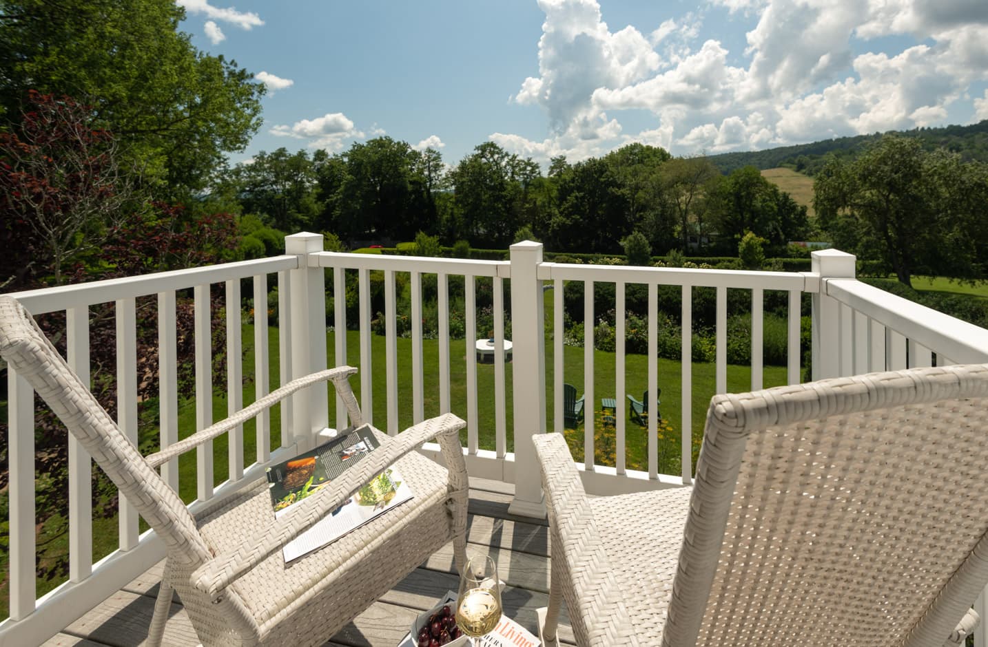 A private second story balcony with two chairs overlooking a garden