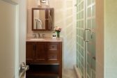 A bathroom sink and mirror next to a walk in shower