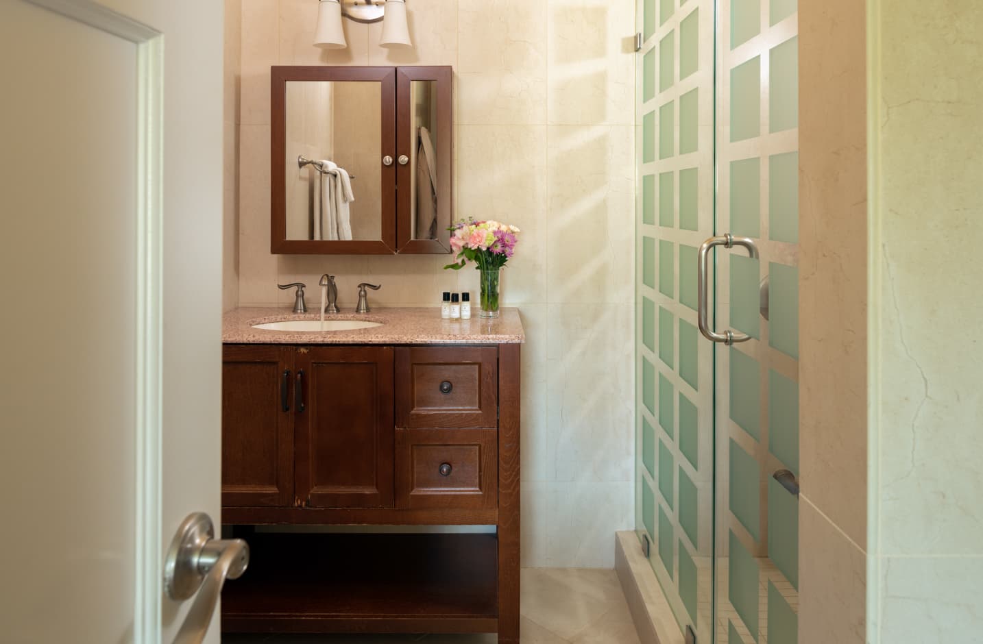 A bathroom sink and mirror next to a walk in shower