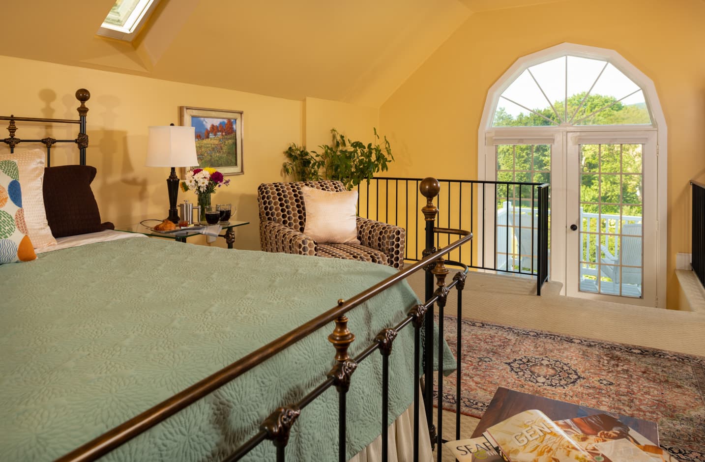 A king bed in a room with a seating area and a window overlooking gardens