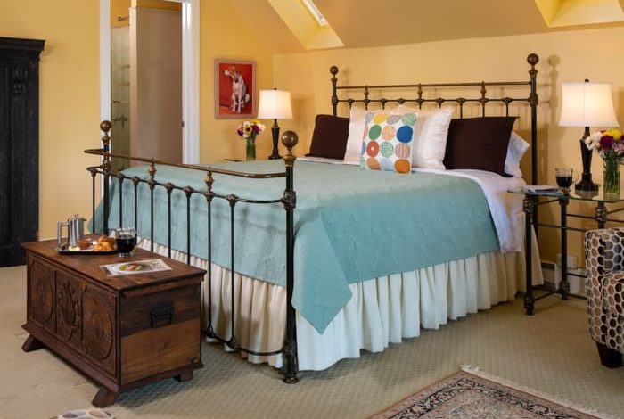 King Bed in a spacious room with yellow walls and a seating area at The Ashby Inn