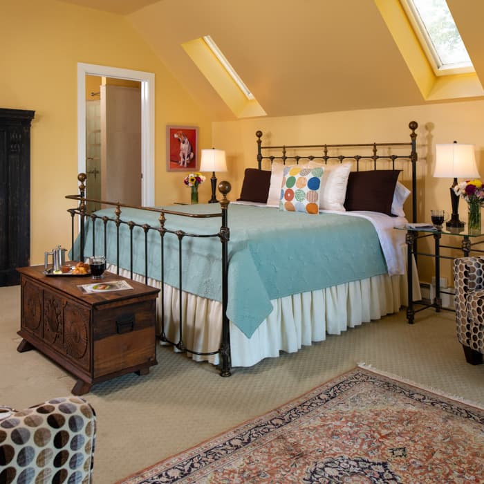 King Bed in a spacious room with yellow walls and a seating area at The Ashby Inn