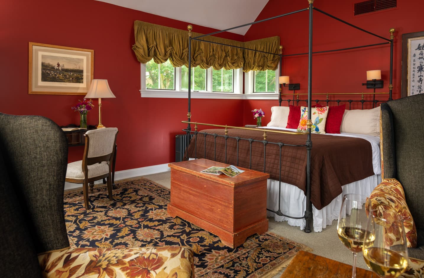 Wrought iron king bed in a room with country furnishing, seating area, and a writing desk