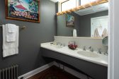 Bathroom with a double vanity sink a large mirror and art on the wall