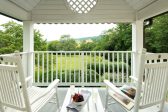 Private porch with Adirondack furniture that overlooks a garden and spectacular views of the Blue Ridge
