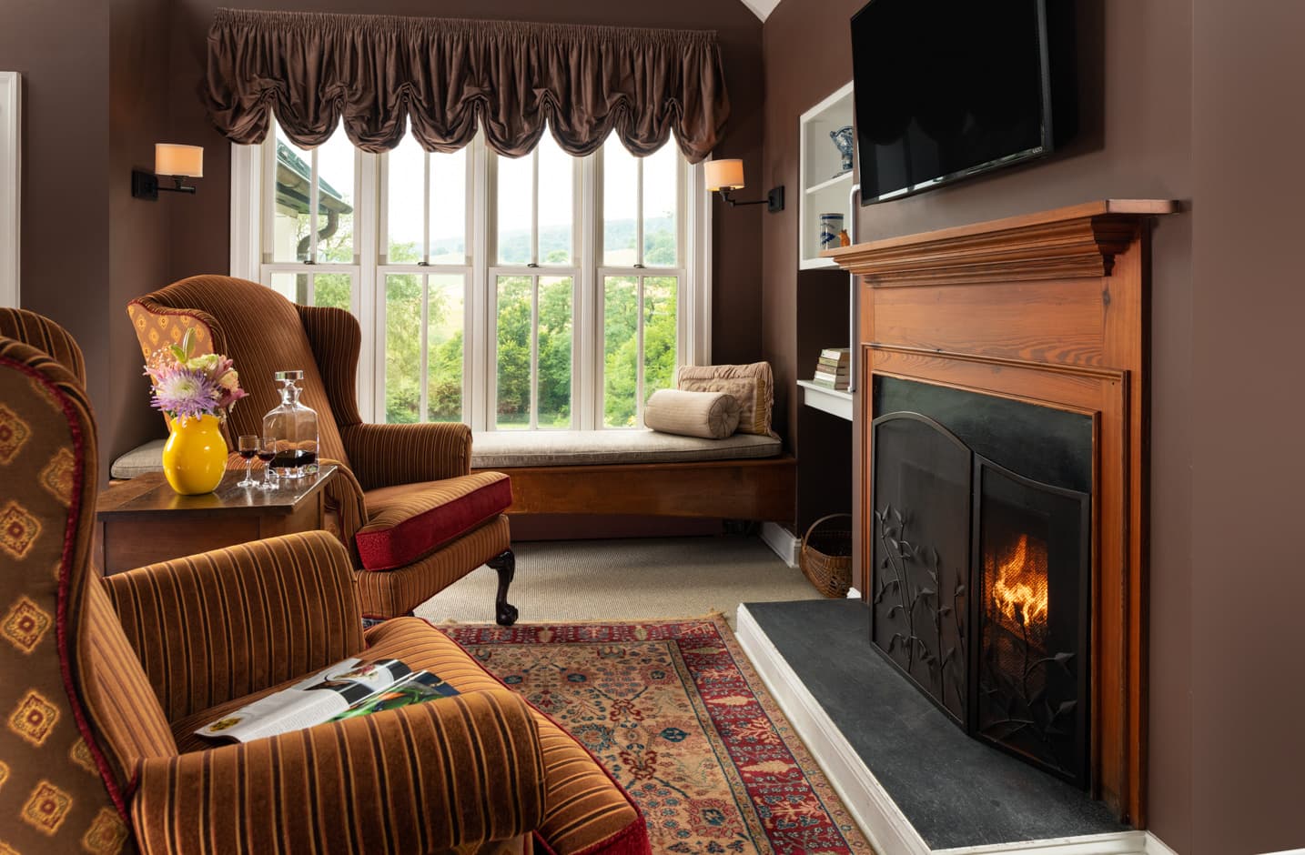 Two chairs facing a wood-burning fireplace and a flat screen TV