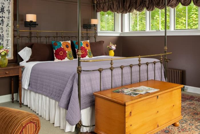 Wrought iron king bed in a room with dark brown walls, and a chest at the foot of the bed