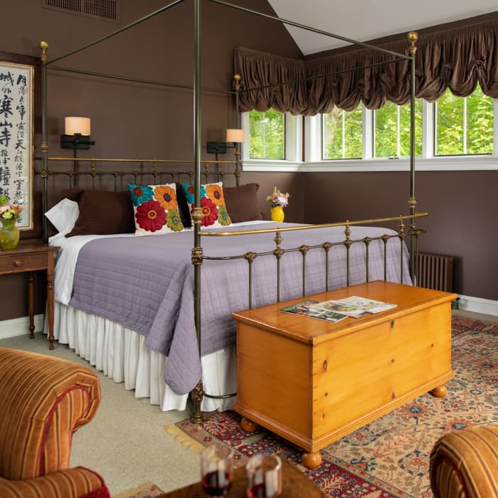 Wrought iron king bed in a room with dark brown walls, and a chest at the foot of the bed