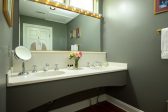 A double vanity sink in a bathroom with a large mirror and a robe hanging on the door