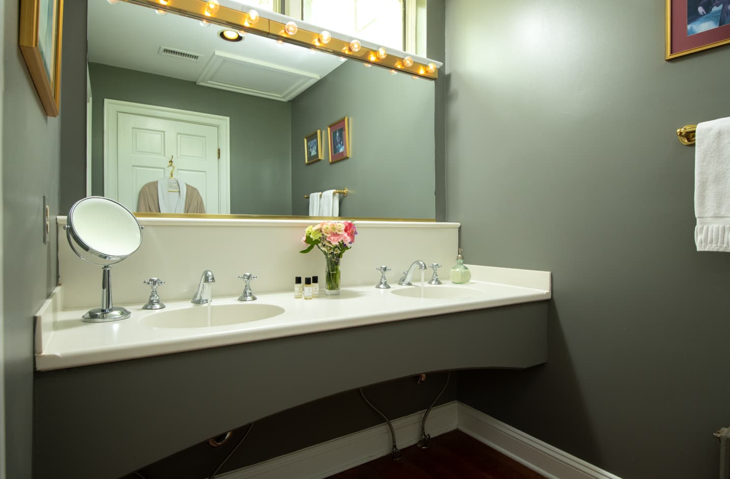 A double vanity sink in a bathroom with a large mirror and a robe hanging on the door