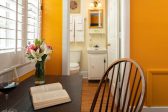 A writing desk with flowers in a vase and a view to the private bathroom