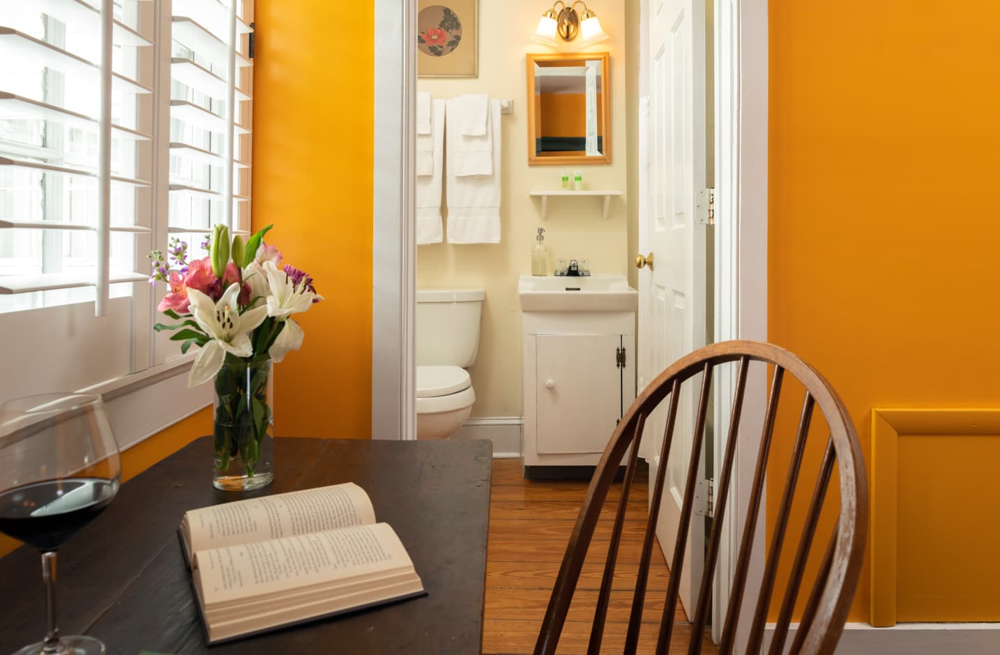 A writing desk with flowers in a vase and a view to the private bathroom