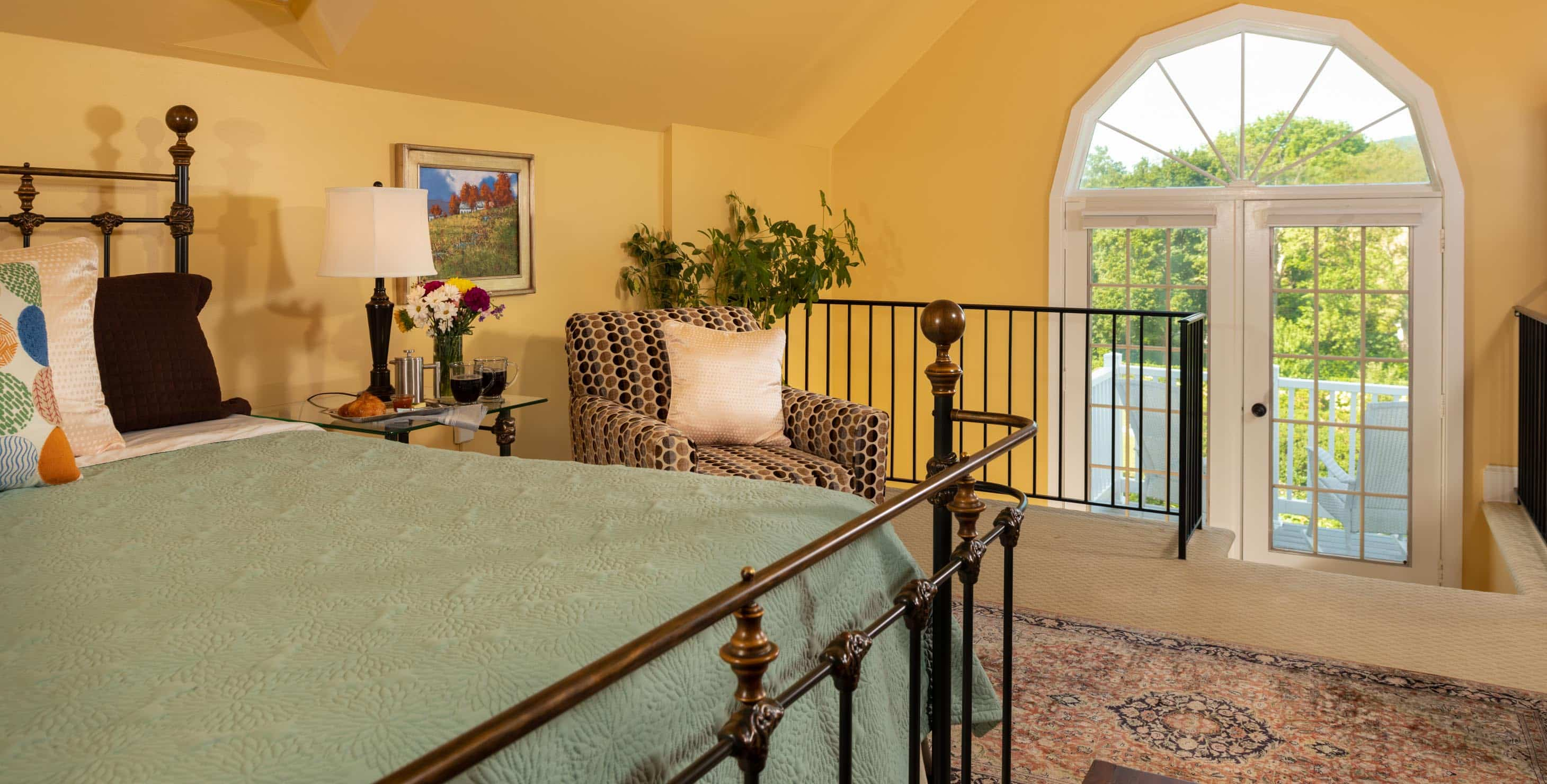 A king bed in a room with a seating area and a window overlooking gardens