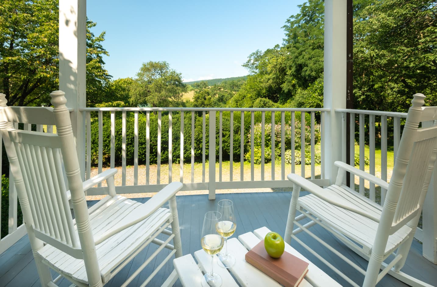 Private porch with Adirondack furniture that overlooks a garden