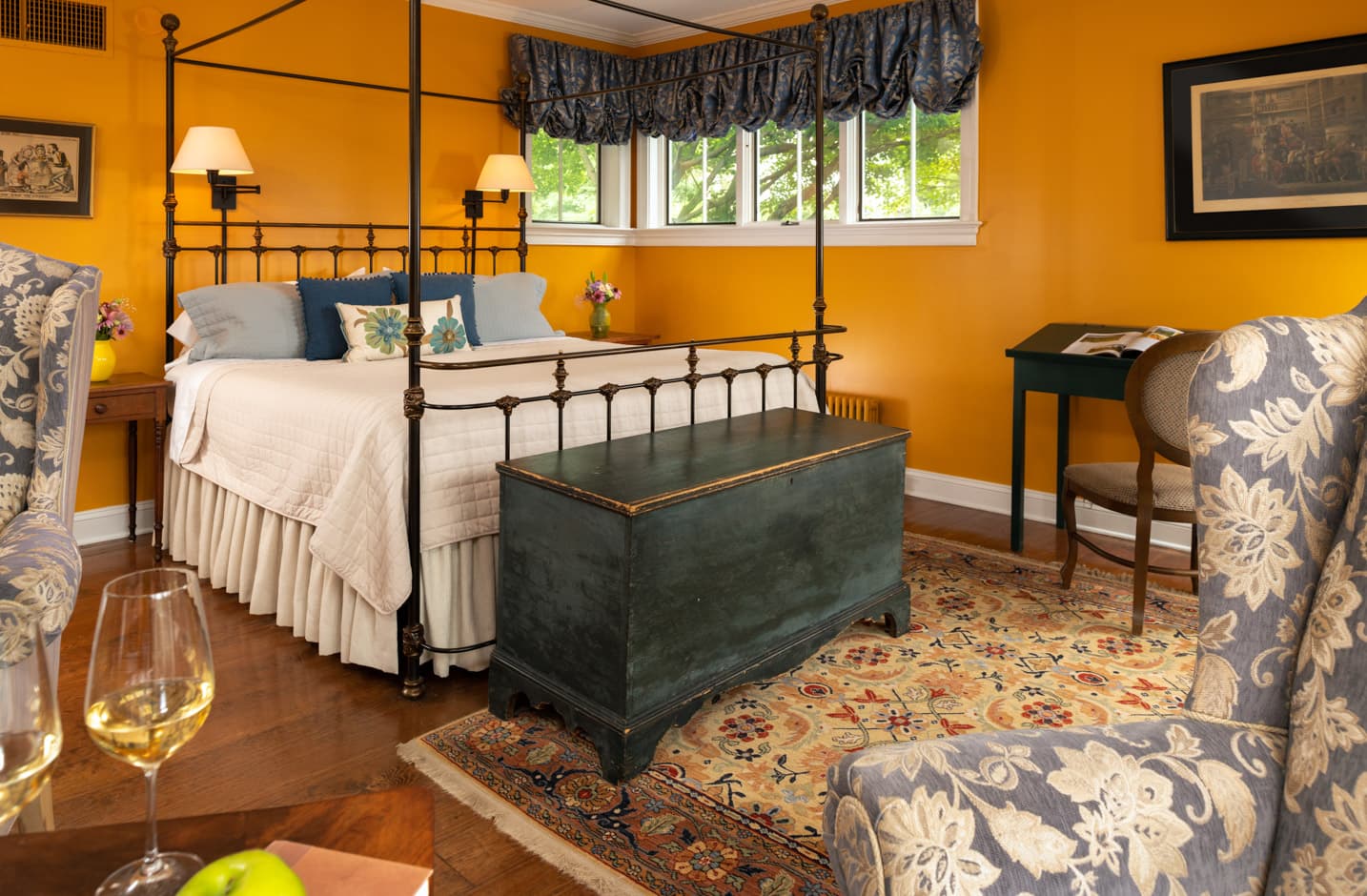 Wrought iron king bed in a room with a seating area and a trunk at the foot of the bed