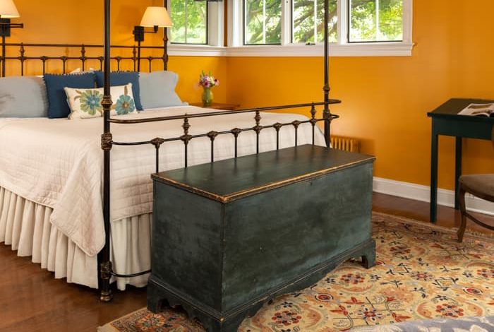 Wrought iron king bed in a room with a seating area and a trunk at the foot of the bed