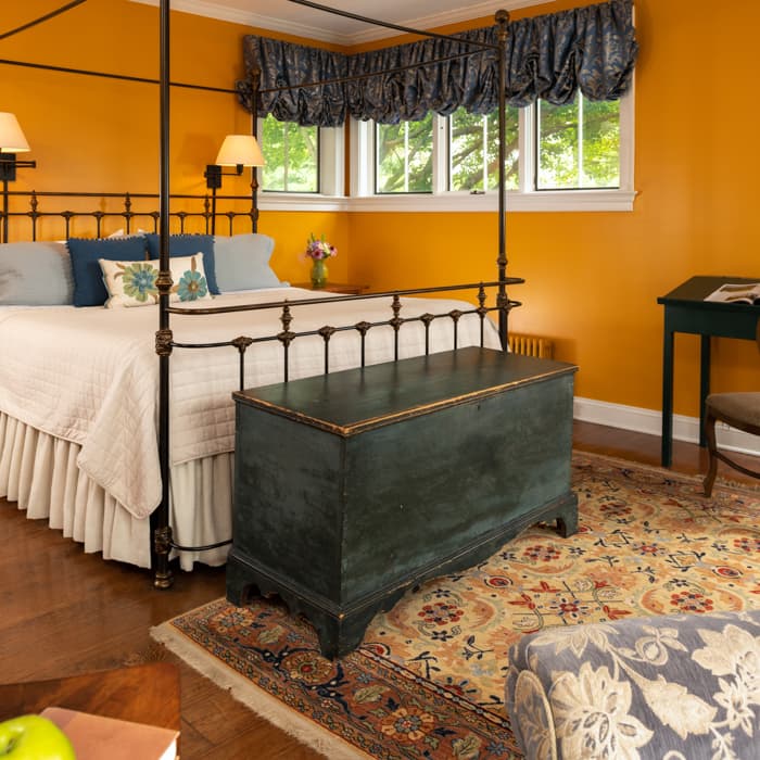 Wrought iron king bed in a room with a seating area and a trunk at the foot of the bed