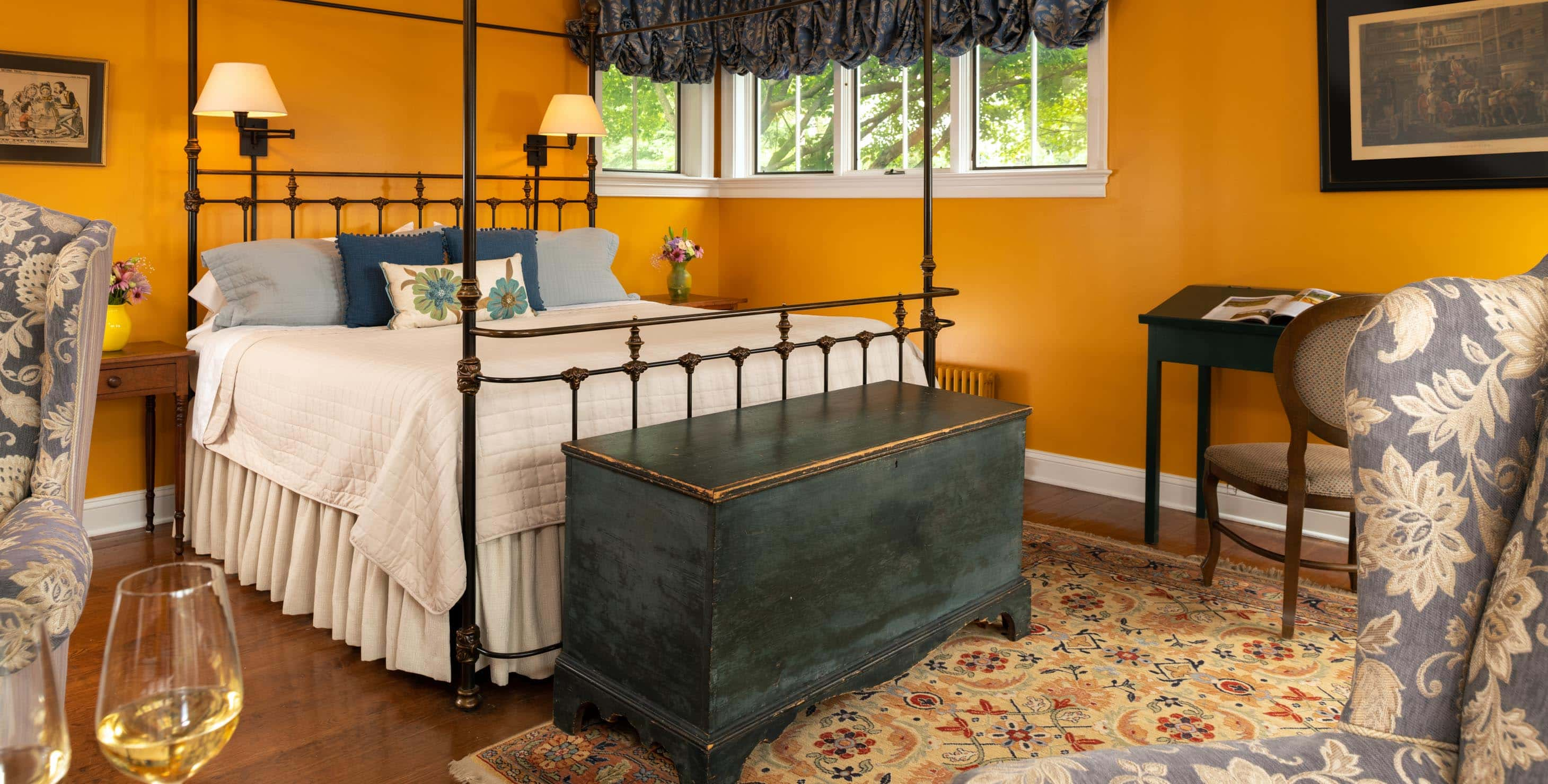 Wrought iron king bed in a room with a seating area and a trunk at the foot of the bed