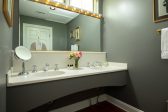 A double vanity sink in a bathroom with a large mirror and a robe hanging on the door