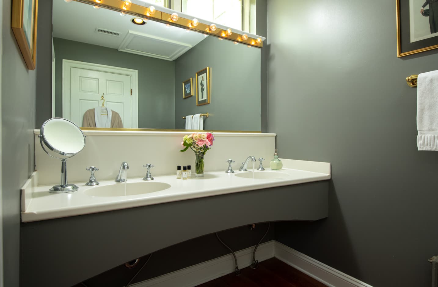 A double vanity sink in a bathroom with a large mirror and a robe hanging on the door