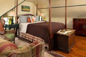 Queen size pencil-post bed in a room with country furnishing and a trunk at the foot of the bed