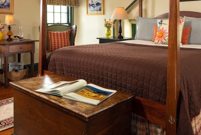 Queen size pencil-post bed in a room with country furnishing and a trunk at the foot of the bed