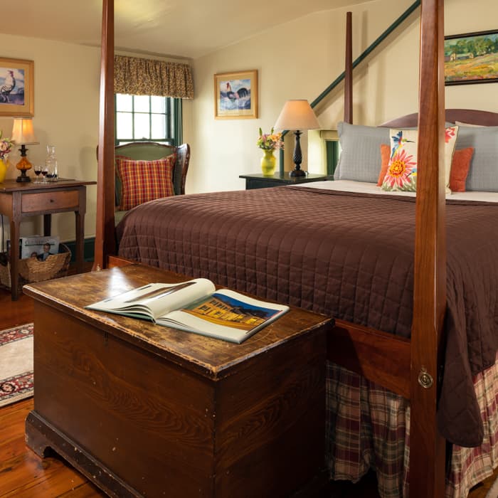 Queen size pencil-post bed in a room with country furnishing and a trunk at the foot of the bed