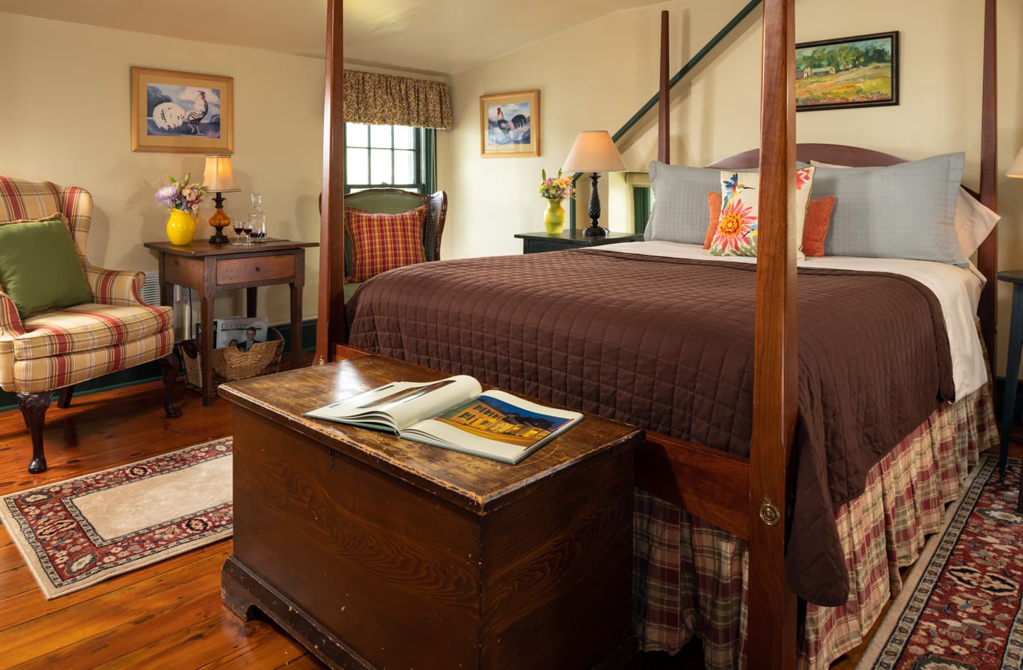 Queen size pencil-post bed in a room with country furnishing and a trunk at the foot of the bed and a seating area for two