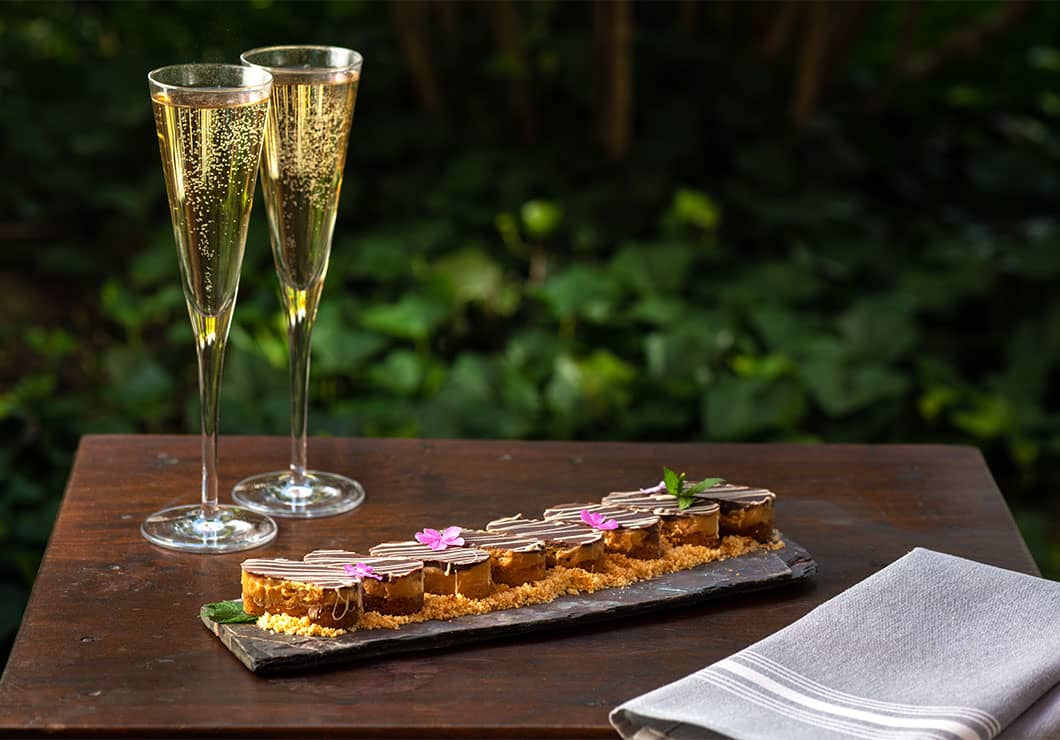 two flutes of champagne and a plate of house-made Ashby chocolates on a table